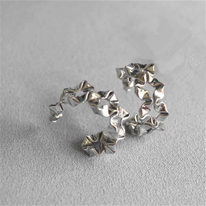 Close-up of silver-tone C-shaped hoop earrings with crinkled metallic texture and floral accent