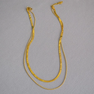 Detailed view of layered gold snake chain necklace with lobster clasp and extender