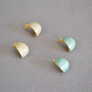 Detail of C-shaped enamel earrings with marble texture in cream and mint green