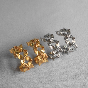 Detailed view of silver and gold C-shape earrings with irregular pleated metal texture
