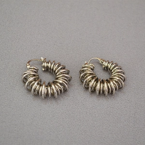 Macro detail of silver spiraled brass hoop earrings with industrial spring texture