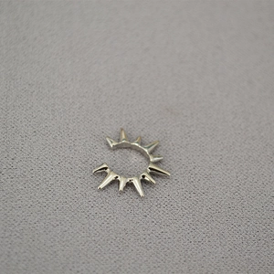 Close-up of a silver-colored spiked ear cuff with minimalist industrial punk style design