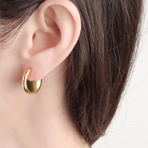 Gros plan d'une boucle d'oreille dorée en forme de C avec finition miroir