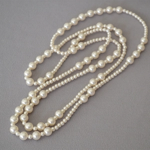 Elegant multi-layer necklace with alternating large and small cream pearls on grey fabric