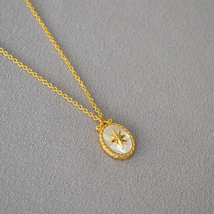 Detailed macro of vintage gold necklace featuring a mother of pearl star oval pendant