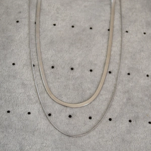 Close-up of double-layer silver snake chain necklaces with flat blade and round link styles