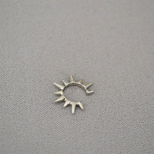 Macro shot of silver spike stud ear cuff with a polished finish on textured background
