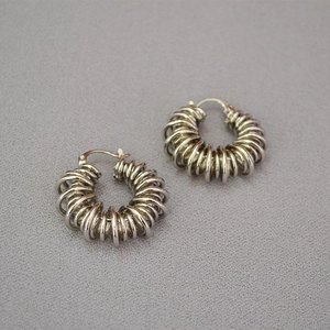 Macro detail of silver spiral coil hoop earrings with polished metal wire texture
