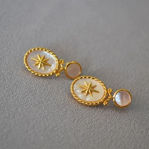 Macro detail of vintage North Star earrings featuring freshwater shell inlay and gold metal
