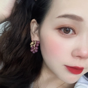 Detailed view of purple grape earrings featuring golden leaf worn by a model