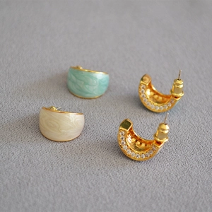 Detail of C-shaped marble enamel earrings with sparkling zircons and gold plating