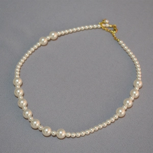 Détail du collier de perles montrant le dégradé asymétrique et le fermoir doré