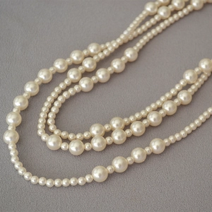 Detail shot of multi-layer pearl necklace with alternating large and small white pearls