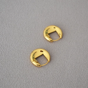 Détail de boucles d'oreilles créoles dorées épaisses avec une finition polie miroir