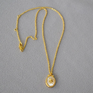 Close-up of vintage gold necklace with oval mother of pearl pendant and star inlay