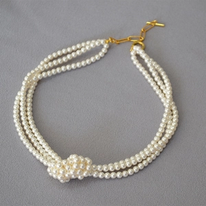 Three-layer glass pearl necklace with decorative knotted design and gold-tone clasp closure