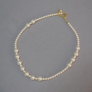 Détail d'un collier de perles avec fermoir mousqueton doré réglable et chaîne d'extension