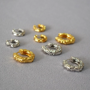 Detailed macro view of gold and silver lava texture hoop earrings in three sizes