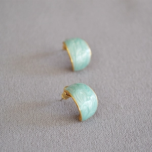 Detailed macro view of mint green enamel marble earrings with gold trim and zircons