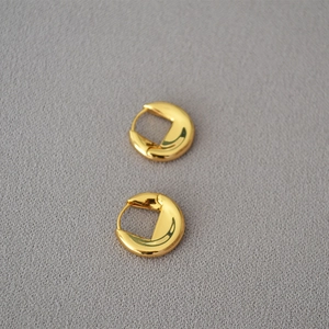 Détail des boucles d'oreilles créoles épaisses en laiton doré avec finition polie miroir