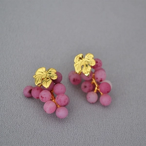 Macro shot of 925 silver stud earrings featuring golden leaves and purple grape beads