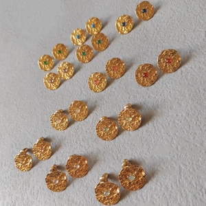 Macro detail of hammered gold stud earrings featuring colorful inset gemstones in a grid