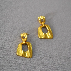Detailed view of hollow trapezoid gold earrings with a hammered vintage texture