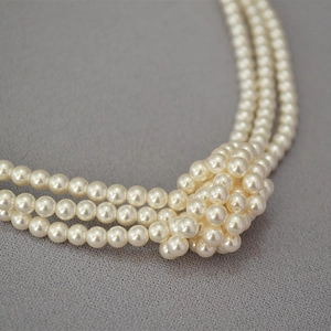 Elegant triple-strand pearl necklace with a vintage decorative knotted weave detail