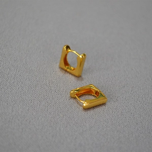 Vue détaillée des boucles d'oreilles carrées géométriques dorées sur fond texturé
