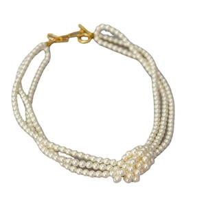 Three-layer pearl necklace with central pearl knot and gold toggle clasp on white background