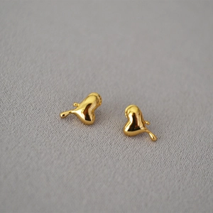 Makroaufnahme flüssiger Herz-Ohrstecker aus Gold mit hochglänzender Spiegeloberfläche