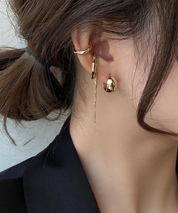 Close-up of gold layered earring set with hoop, twisted ring and tassel ear cuff on model