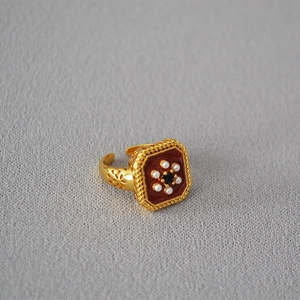 Detail of vintage square gold ring with red enamel, center black gem and pearls