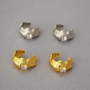 Detailed view of gold and silver textured ear cuffs with sparkling zircon stones