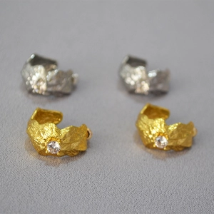 Detailed macro view of textured C-shaped earrings with central cubic zirconia inlay