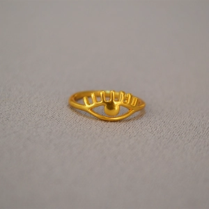 Macro shot of gold-plated brass eye-shaped ring with hollowed radial eyelash details
