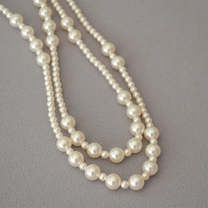 Detailed view of layered necklace with alternating sizes of lustrous white pearls