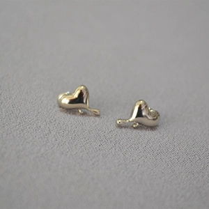 Makroaufnahme minimalistischer goldener Herzohrringe mit flüssigem Metall-Design