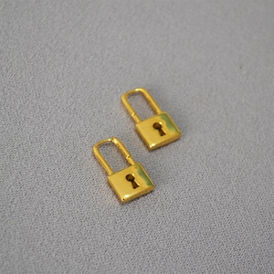 Polished gold plated padlock drop earrings with keyhole detail on grey fabric background