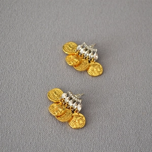 Dettaglio macro di orecchini a moneta d'oro vintage con perni in cristallo e ritratti