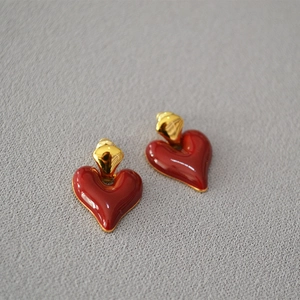 Detailed close-up of vintage heart earrings with red enamel glaze and gold metal base