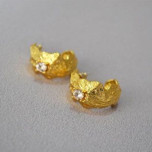Macro detail of gold hammered texture C-shape earrings featuring brilliant zircon stones