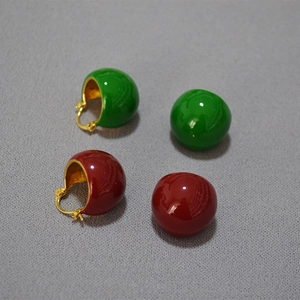 Détail macro de boucles d'oreilles émaillées rétro en rouge et vert avec plaqué or