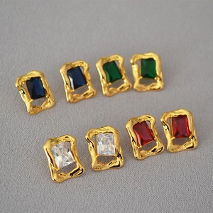 Close-up of four rectangular colored gemstone stud earrings with vintage gold textured borders