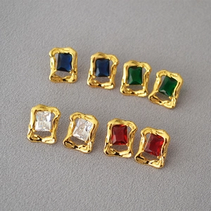 Flat lay of four pairs of vintage brass rectangle earrings with colorful cubic zirconia