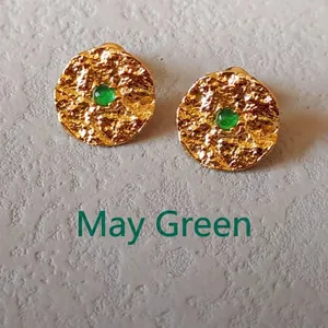 Detailed macro view of May birthstone stud earrings with green gems and gold hammered texture