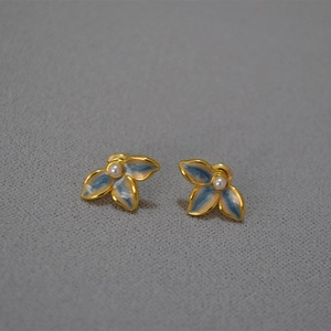 Detailed macro view of handmade enamel leaf earrings with center pearls and gold plating