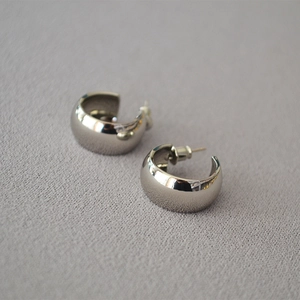 Macro view of wide C-shape silver earrings with a high-polished mirror finish