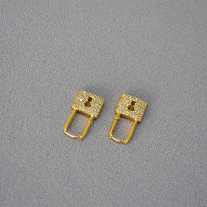 Detailed macro view of gold-plated padlock earrings with micro-pave sparkling zircons