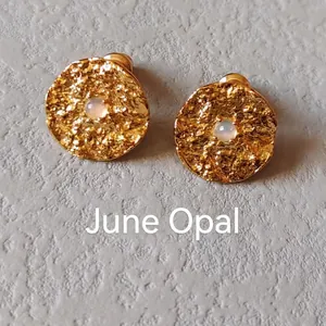 Detail view of round hammered gold stud earrings with a June Opal gemstone center